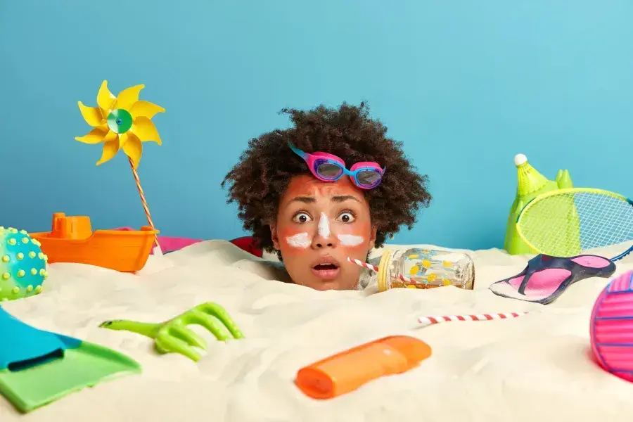 A young woman head coming our of a sand and looking frazzled. Surrounded with holiday items