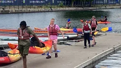 Young people carrying Kayak outside the water